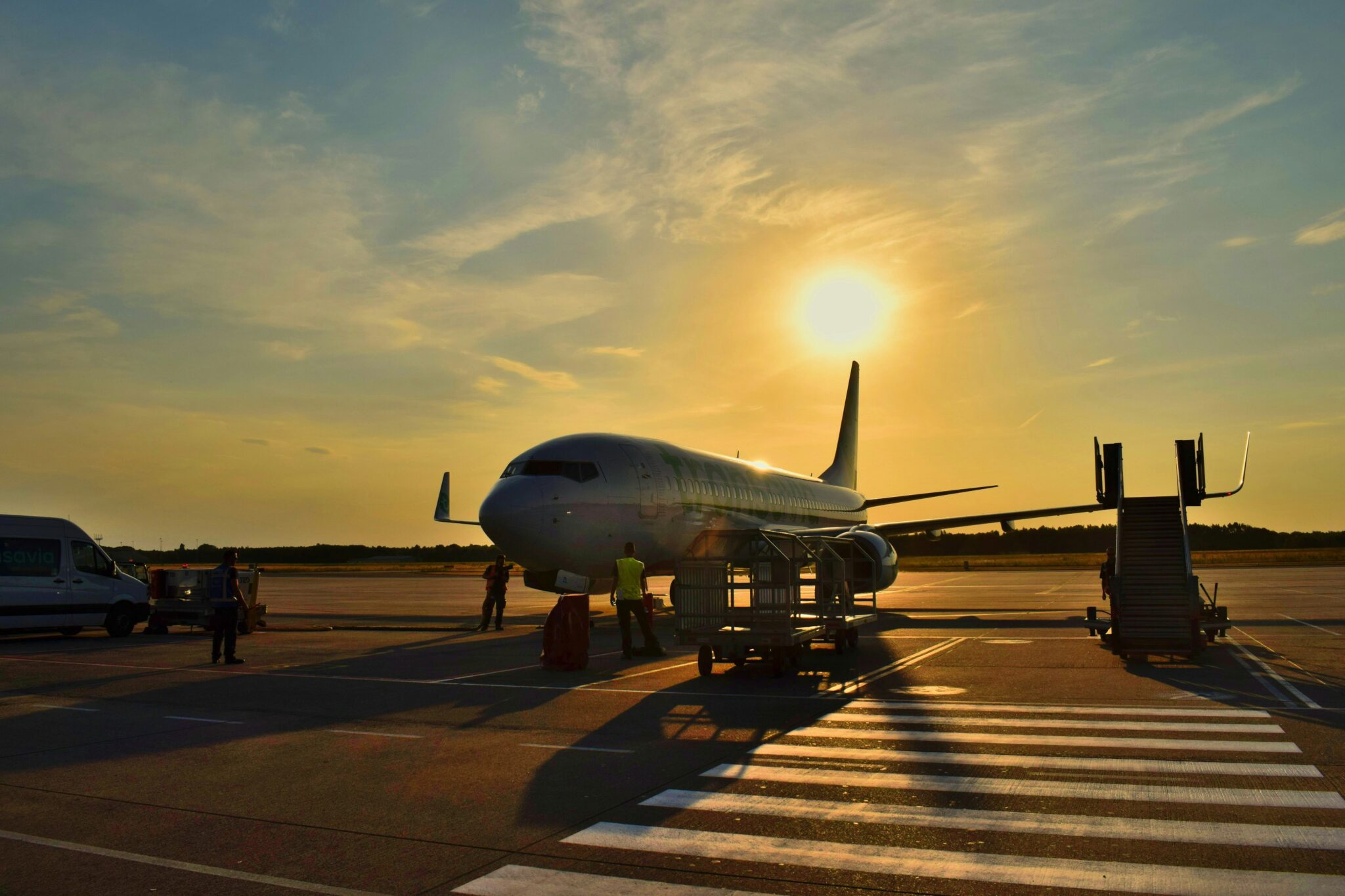 Plane on the tarmac with the sunset behind it.