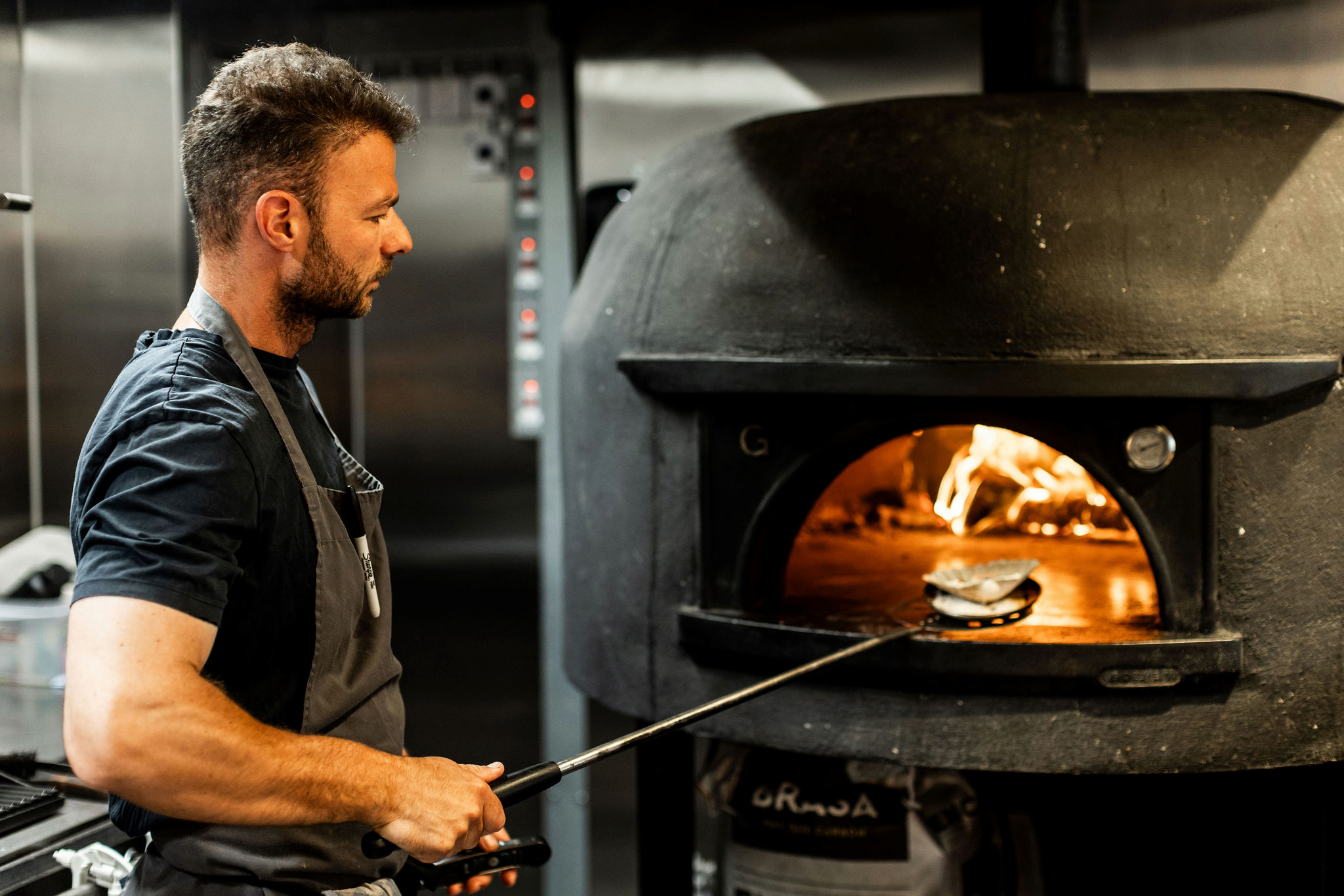 A chef using a pizza oven.