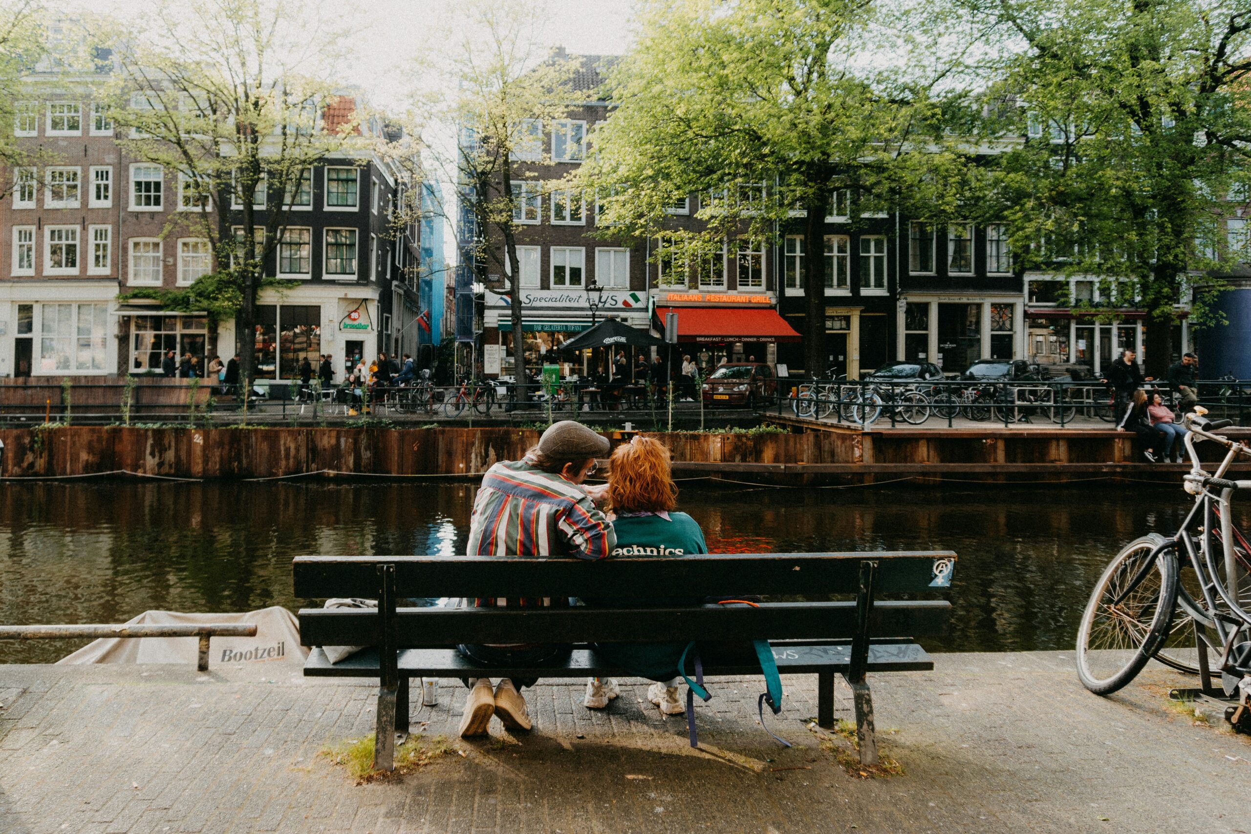 Couple sat on a bench along the canal in Amsterdam.