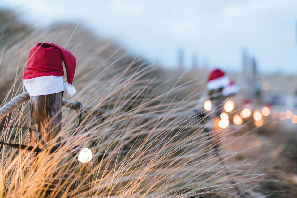 Santa hats along a fence at the beach.